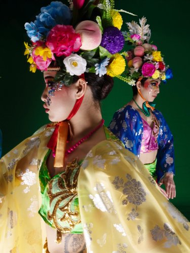  a woman in traditional yellow clothing with two other women behind her.
