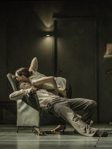 A man slipping from the armchair while the woman kisses him.