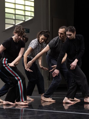 cinq danseurs à la suite dans la même position, regardant leurs mains