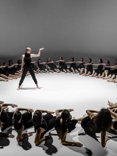 une danseuse au centre d'un grand cercle formé par des danseurs alongés sur scène