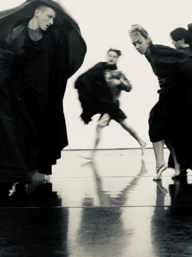  several dancers performing in flowing black costumes