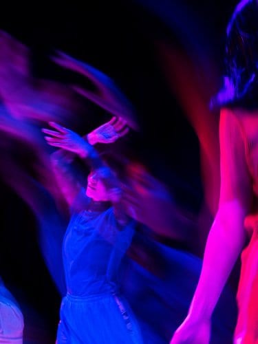 People dancing in blue and pink lights.