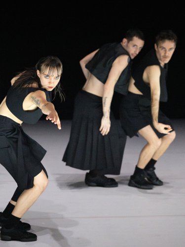 4 dancers performing on stage wearing black