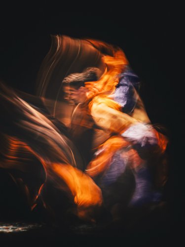 Two blurred figures of dancers with orange light effects