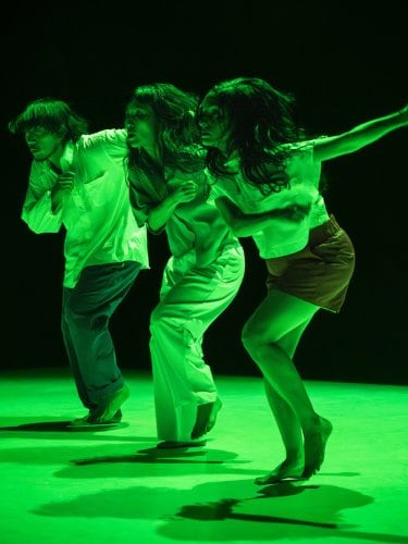 Three dancers under green stage light