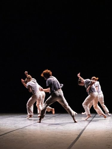 dancers running, wearing white, black scenography