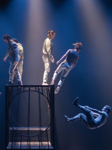 Dancers levitating around a metal cage on stage