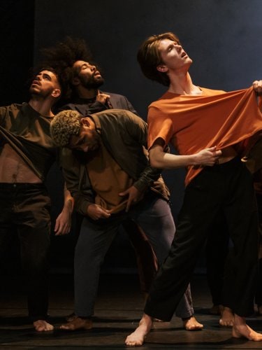 Group of six dancers in a circle lifting their t-shirts