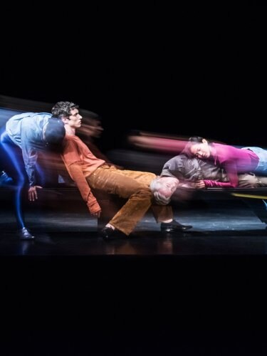 Danseurs assis les uns sur les autres dans des tenues colorées