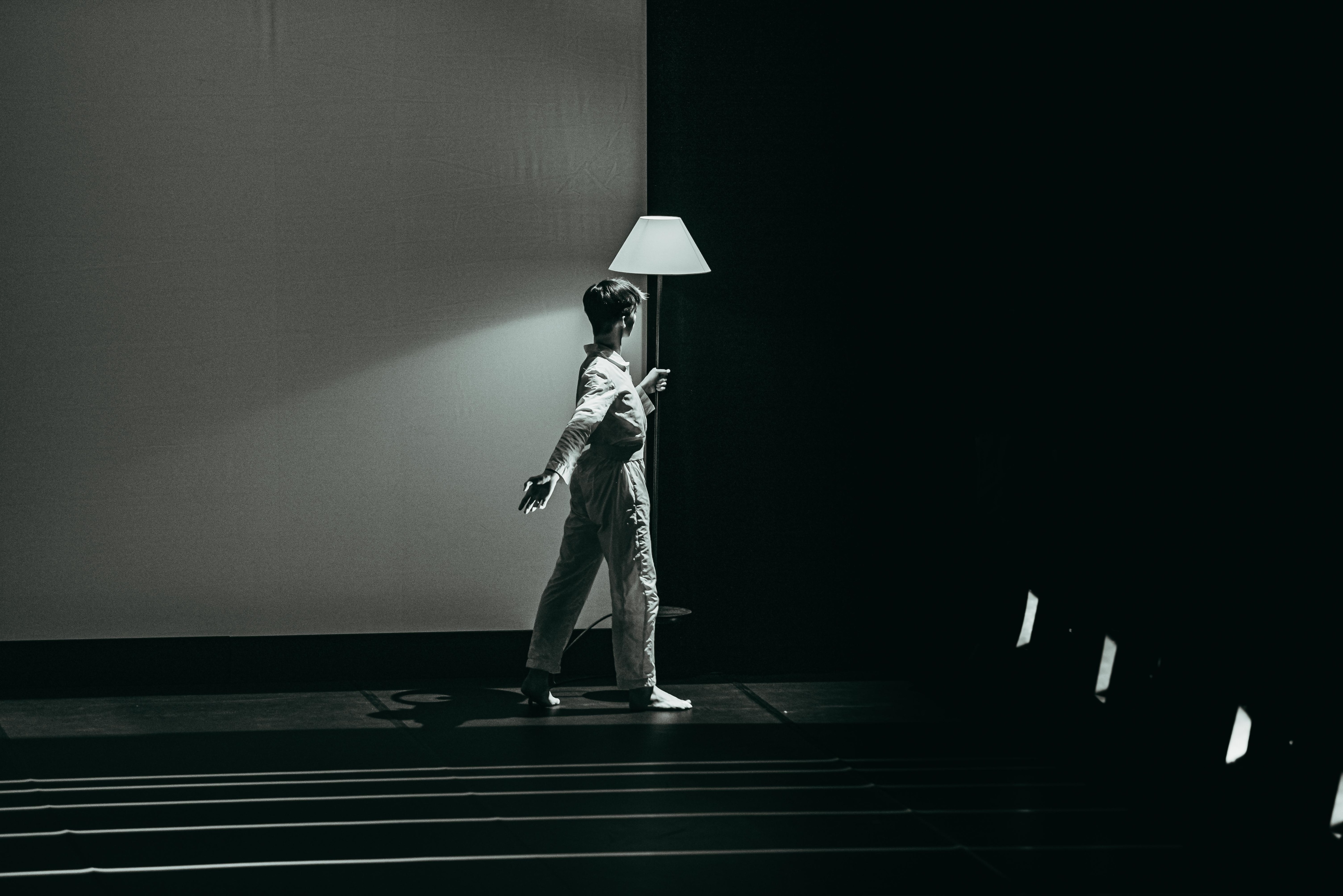 一名舞者背影的黑白照，舞者面對一盞燈，表演Andy De Groat的作品《Red Notes》。