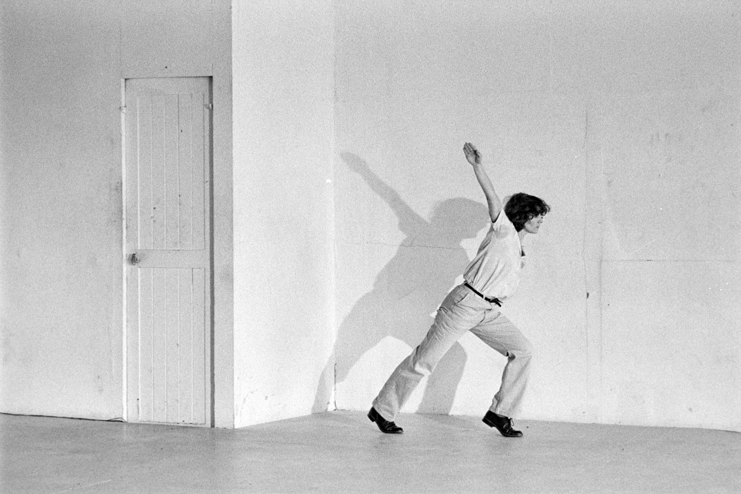 dancer in white, arm raised backwards, on a white background