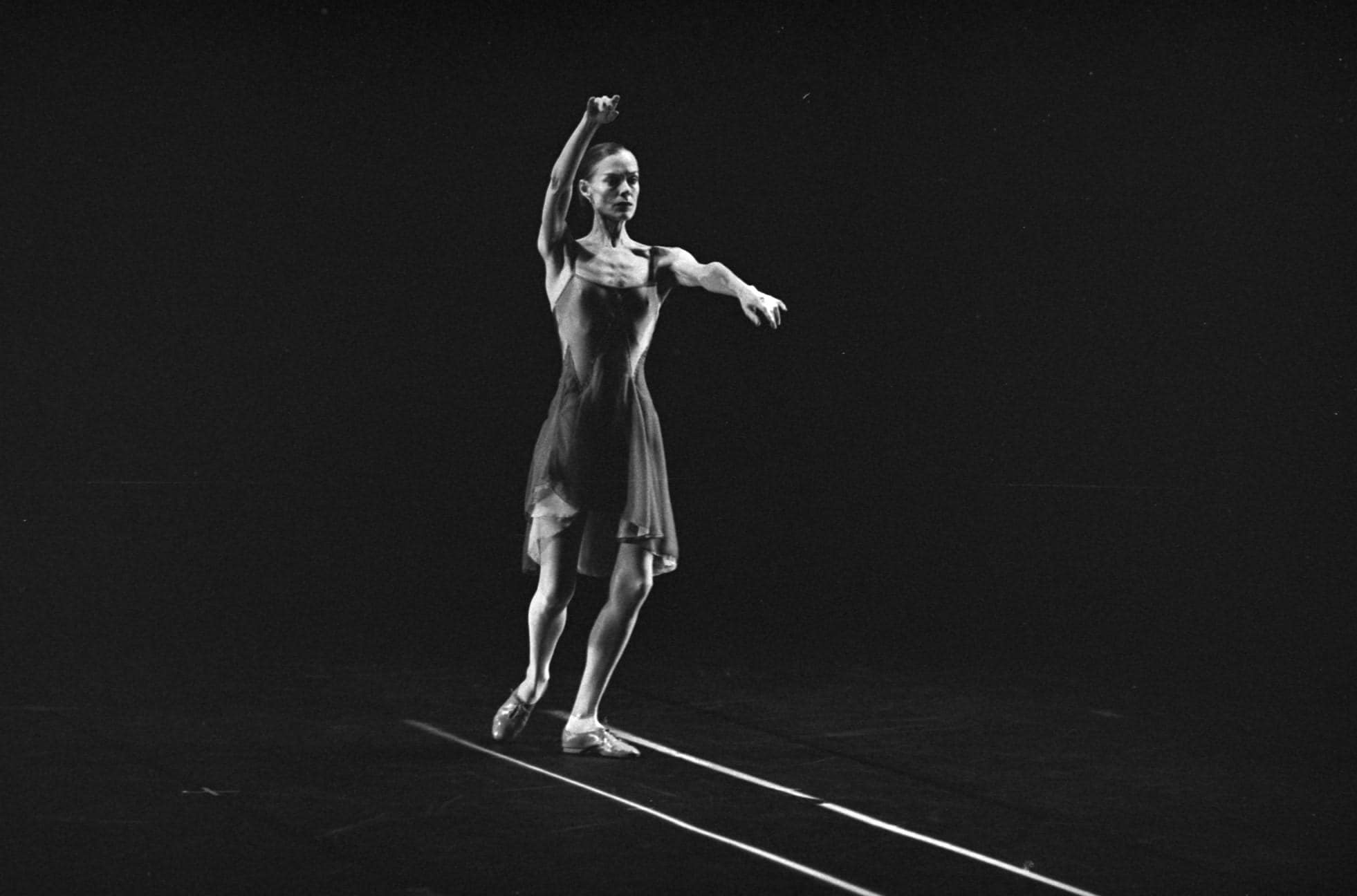 Dancer with arms in the air, following two parallel lines on the floor.
