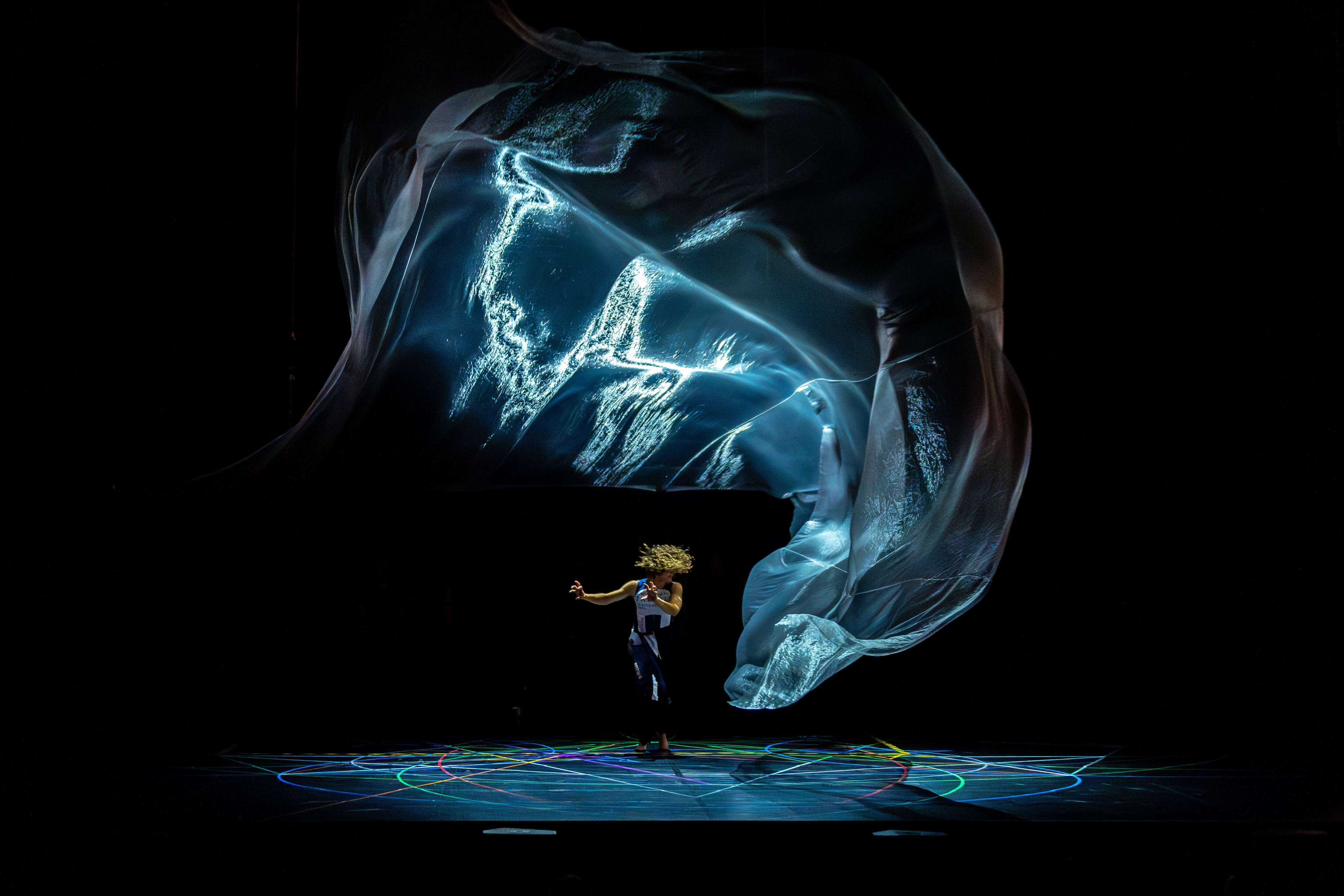 Dancer in profile under a light projection on stage