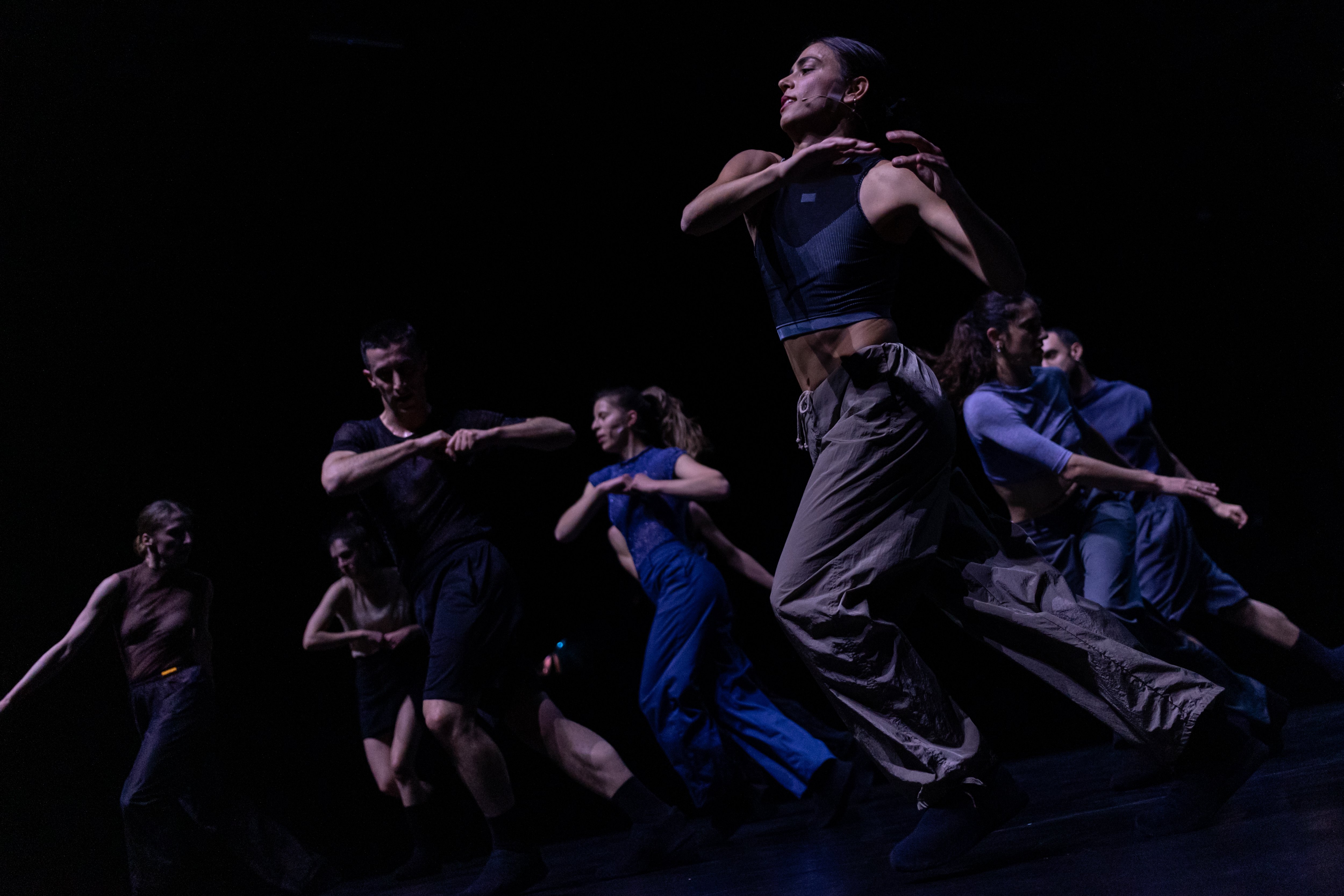 seven people running to the left on a black background