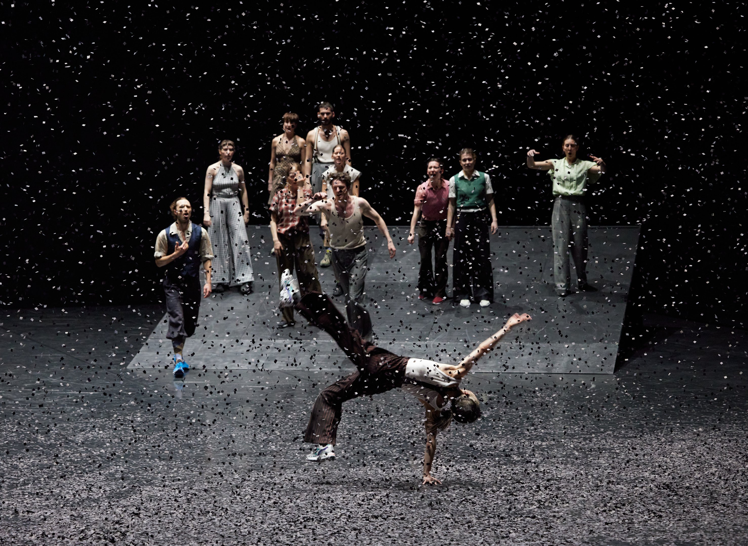 groupe de danseurs en fond, une femme au sol sous des confettis