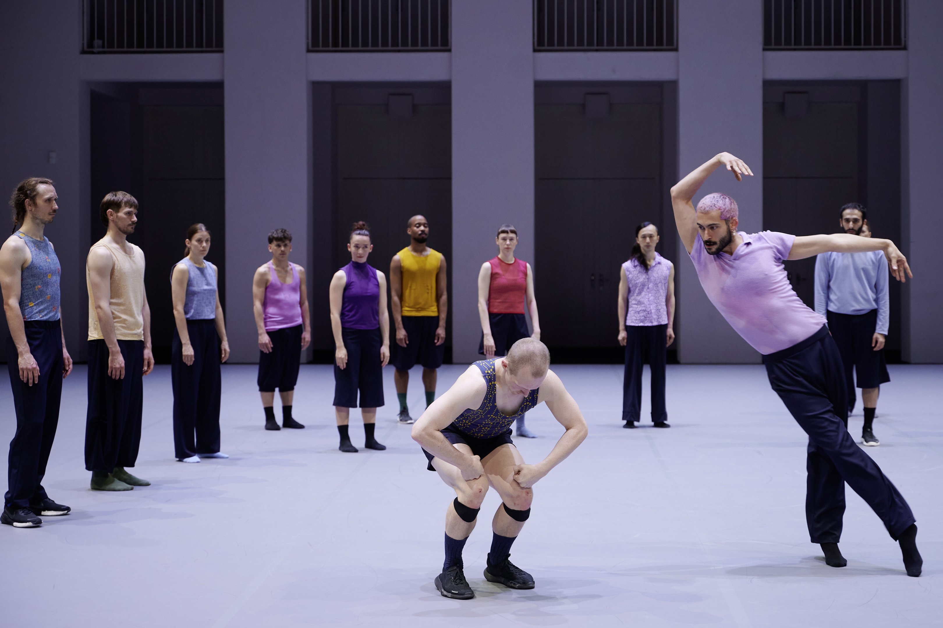 deux danseurs dont un recroquevillé et les autres danseurs les regardent dans le fond