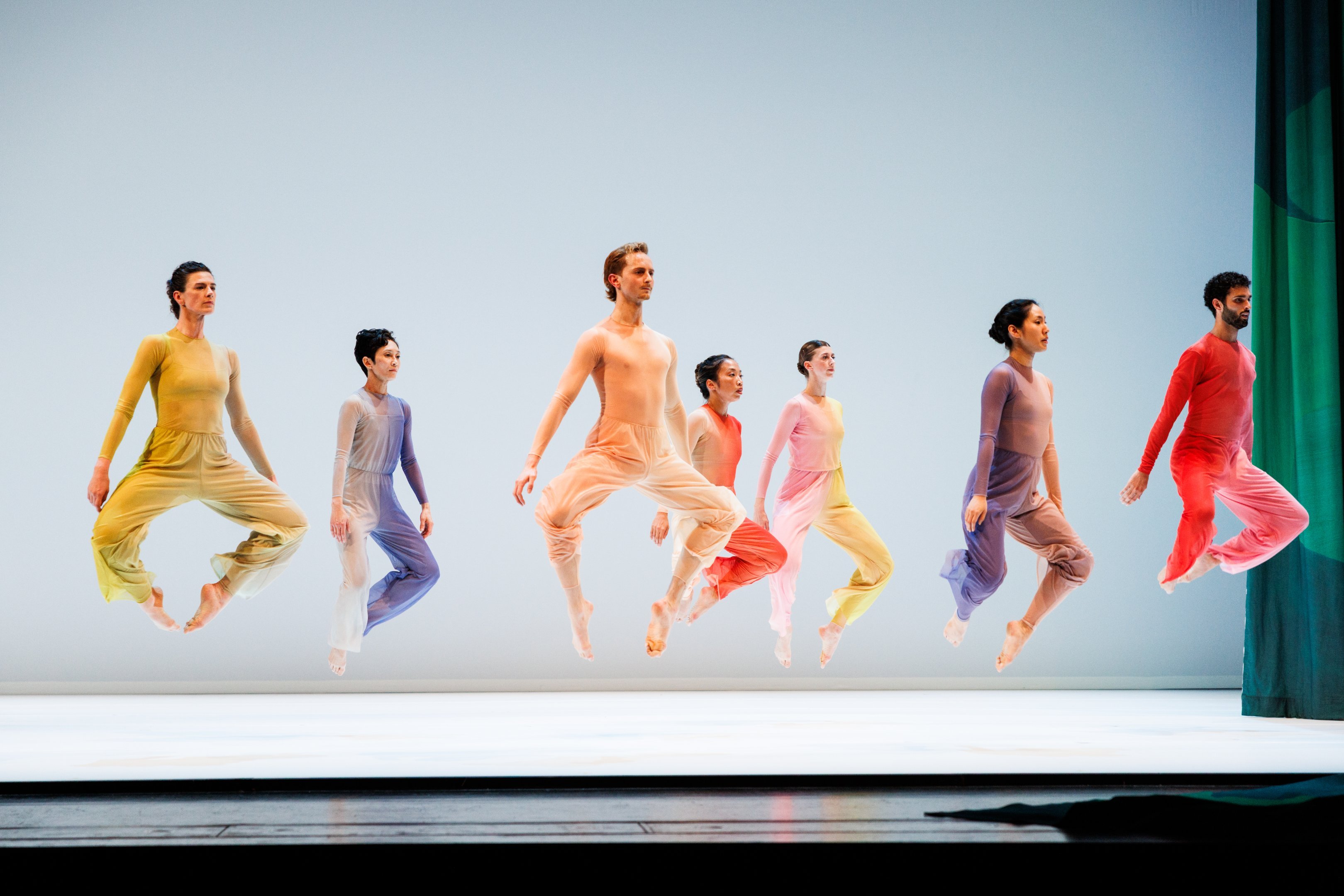 Seven dancers jumping and facing to the right