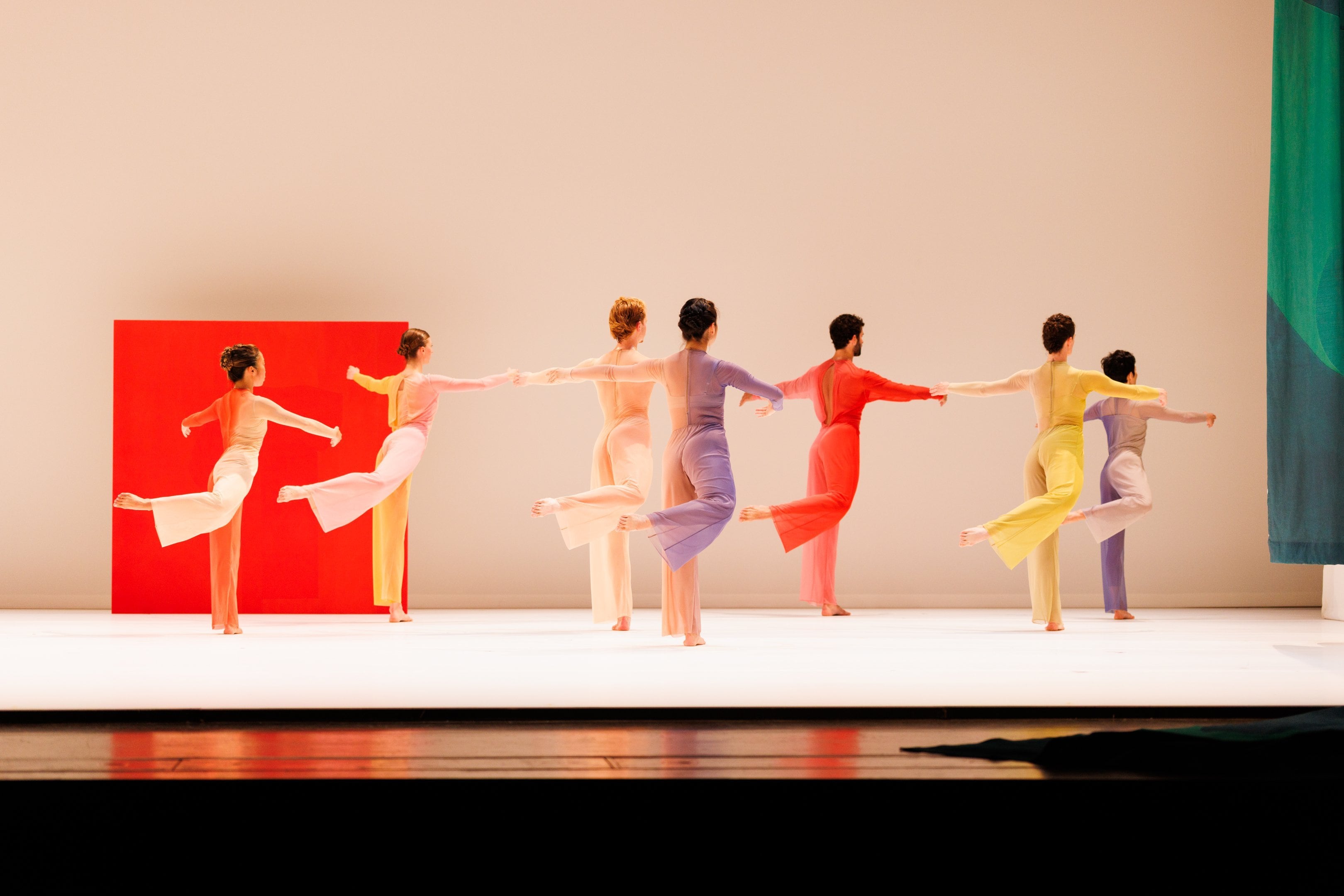 A group of dancers facing towards the back in a diagonal line to the right, all in the same position