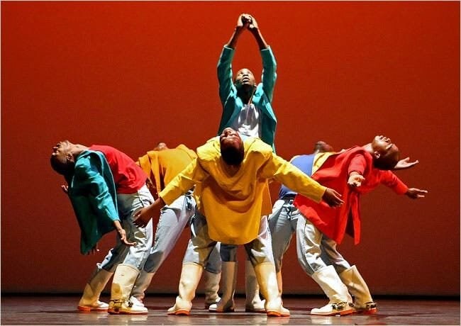 un groupe de danseurs performant devant un fond rouge