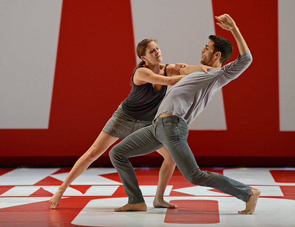 Photo d'une représentation du spectacle Reflections montrant deux danseurs sur un fond rouge et blanc