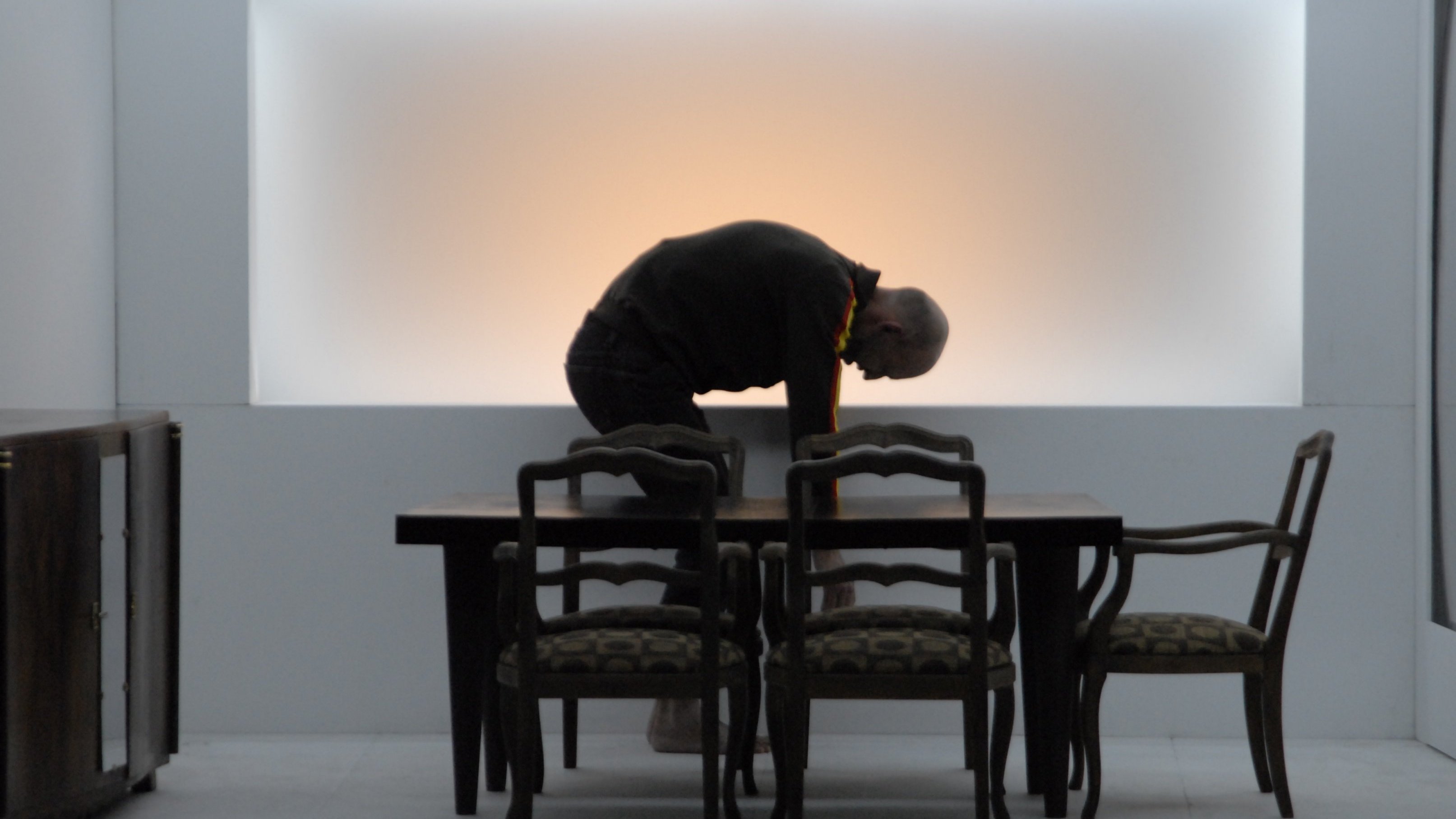 Homme entrain de se baisser derrière une table.
