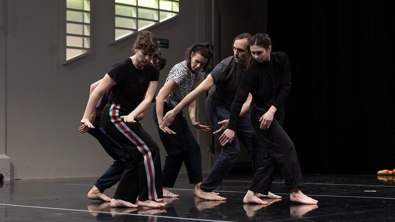 cinq danseurs à la suite dans la même position, regardant leurs mains