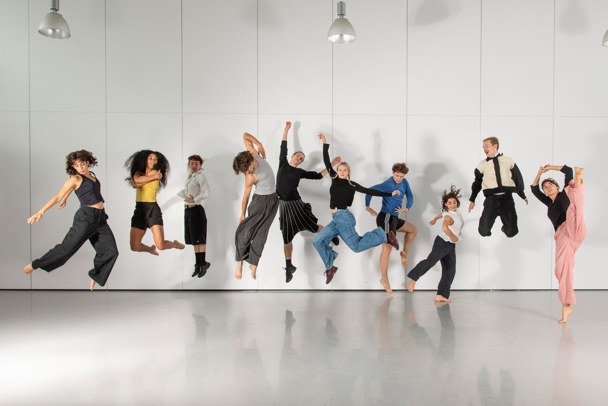 Ten dancers jumping on a white background.