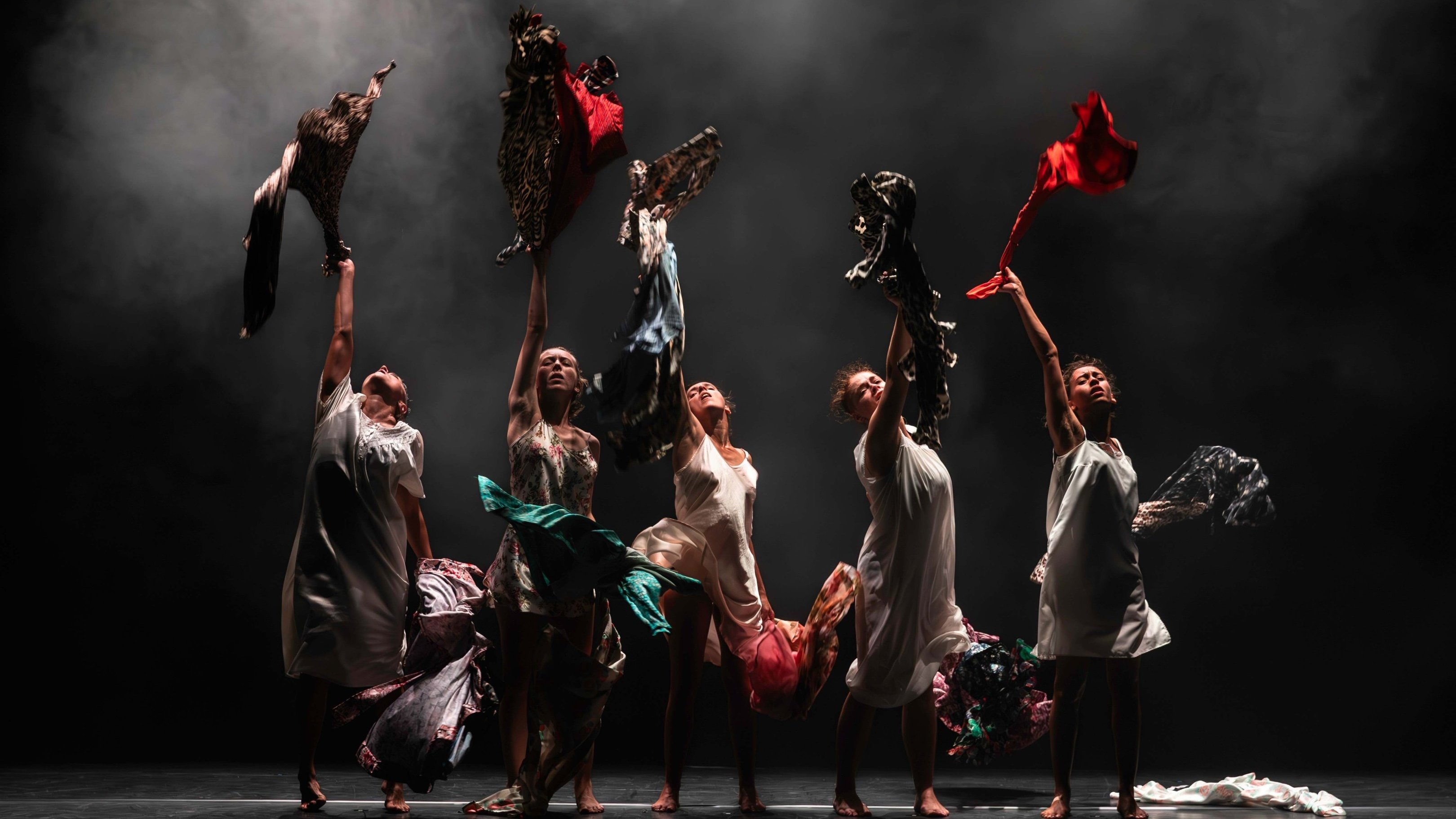 Quatres femmes alignées qui lancent des chemises et des robes vers le haut