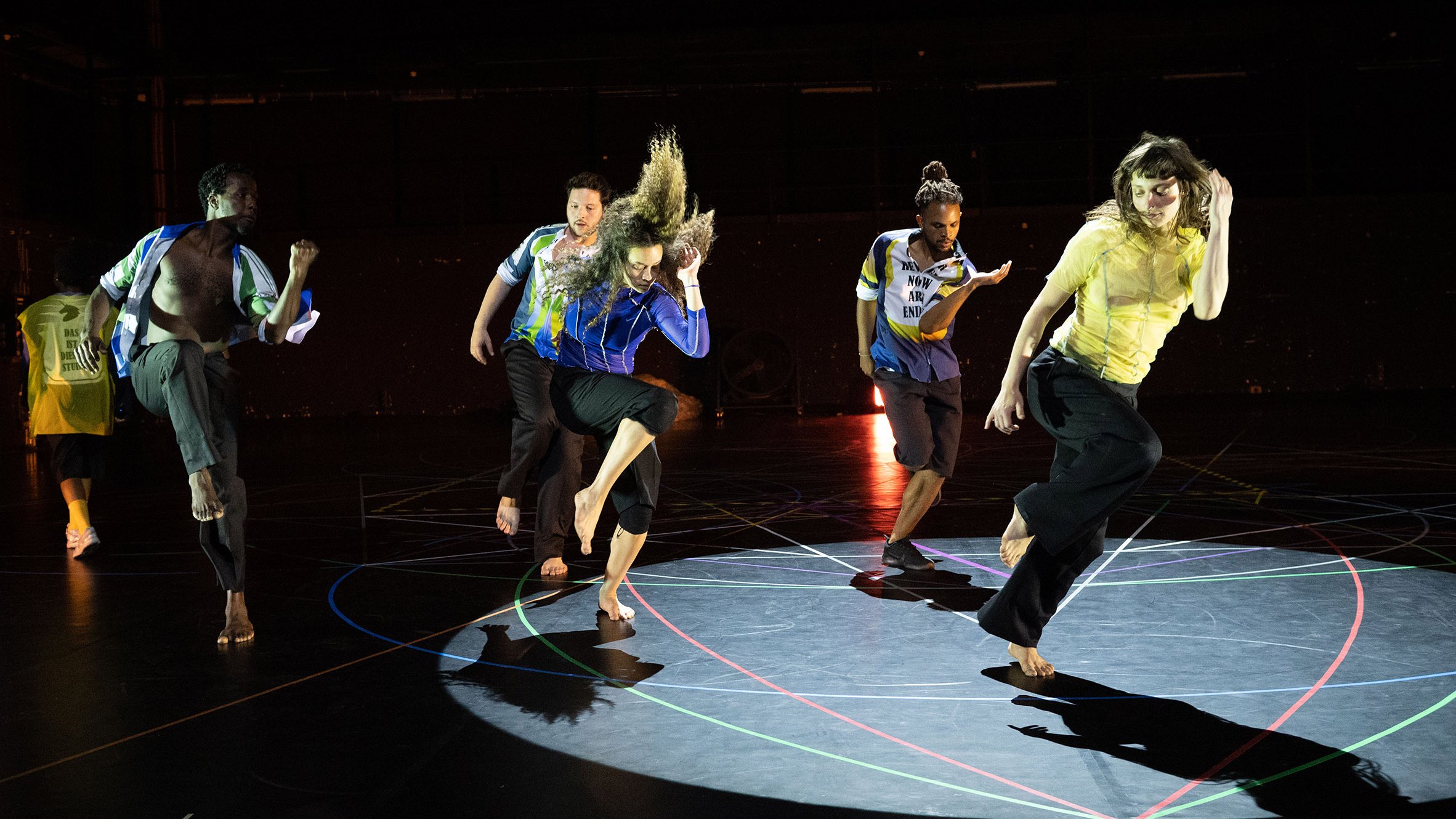 A group of dancers in the same position, in a one-legged jump.