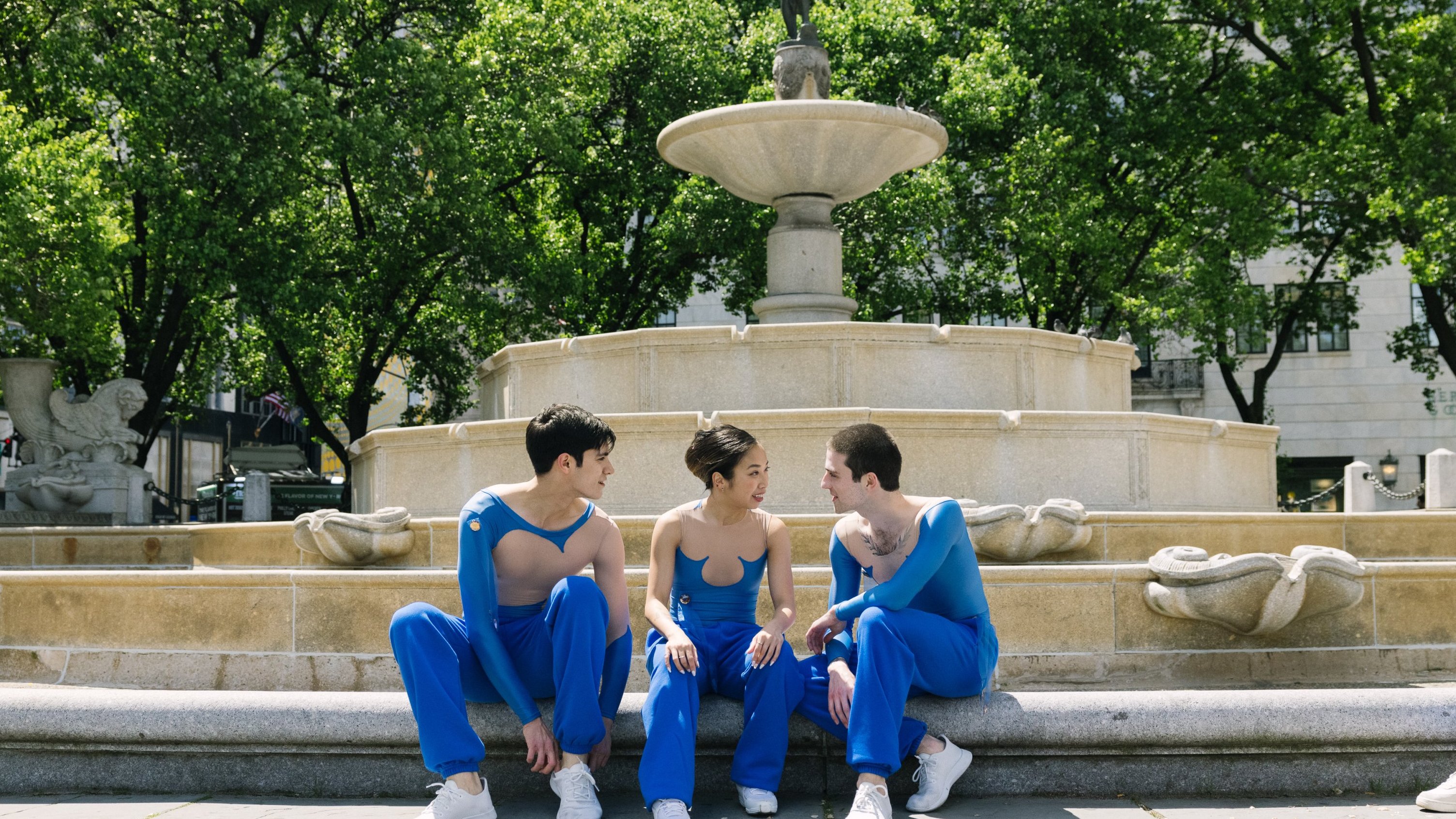 3 dancers sitting in front of the Pulitzer Fountain