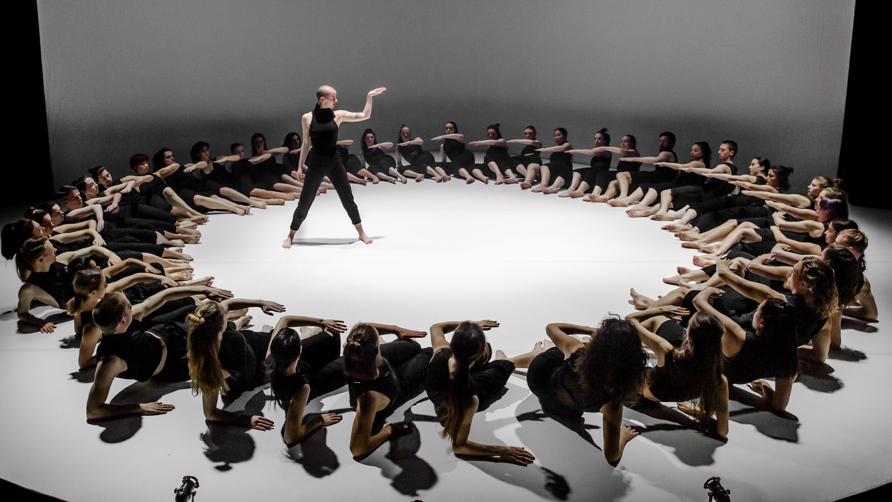 une danseuse au centre d'un grand cercle formé par des danseurs alongés sur scène