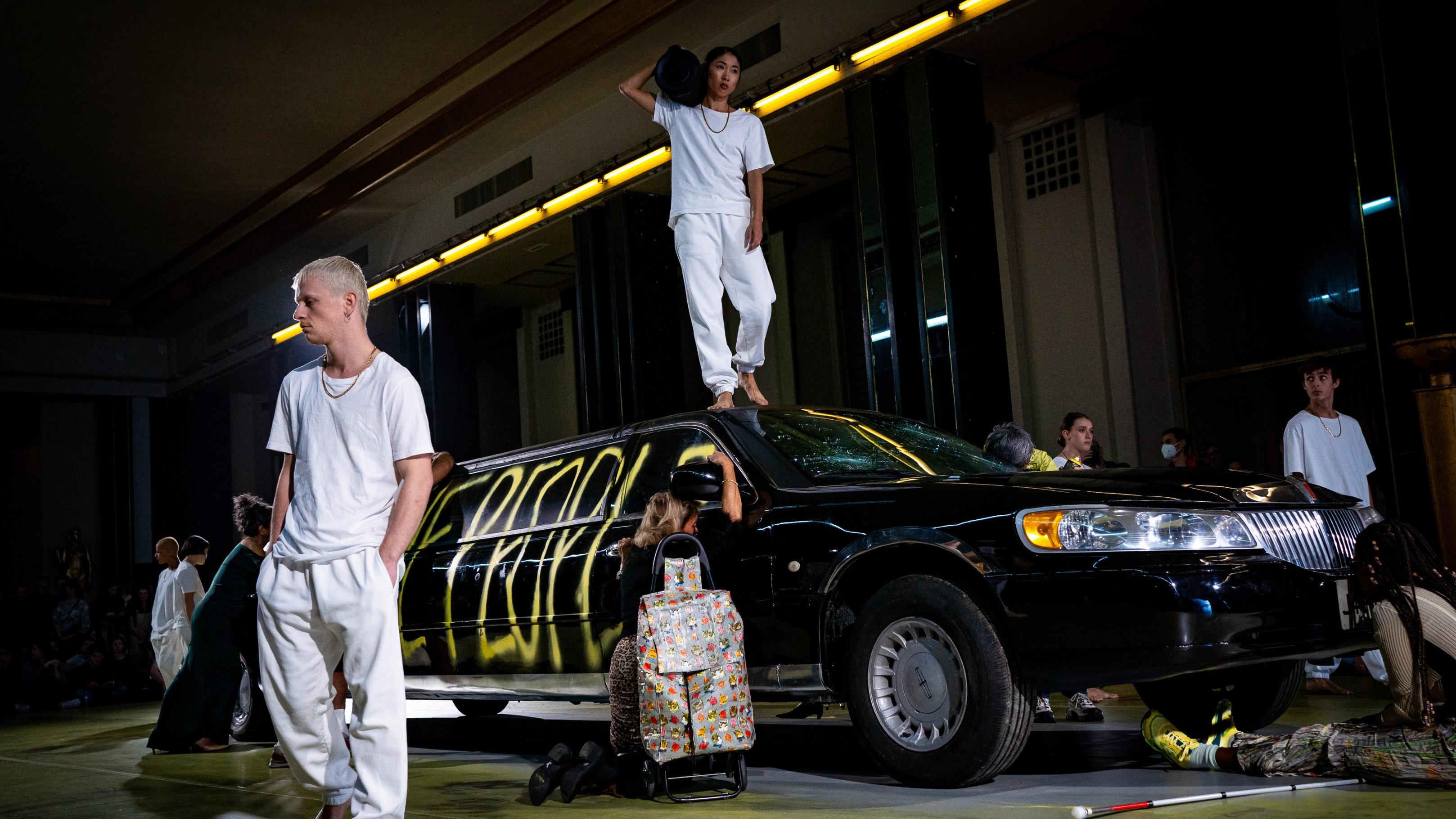 dancers on stage in front of a car