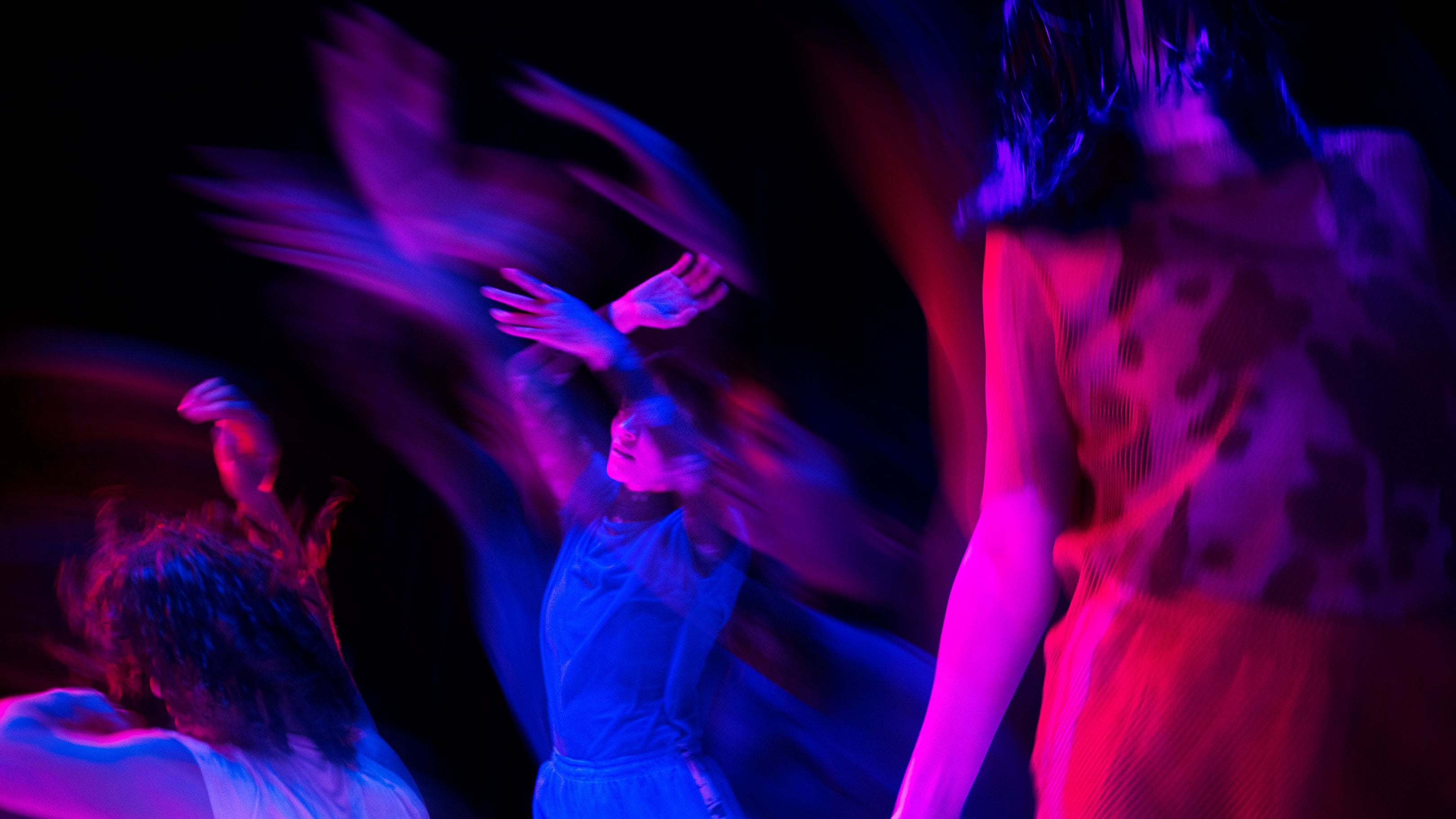 People dancing in blue and pink lights.