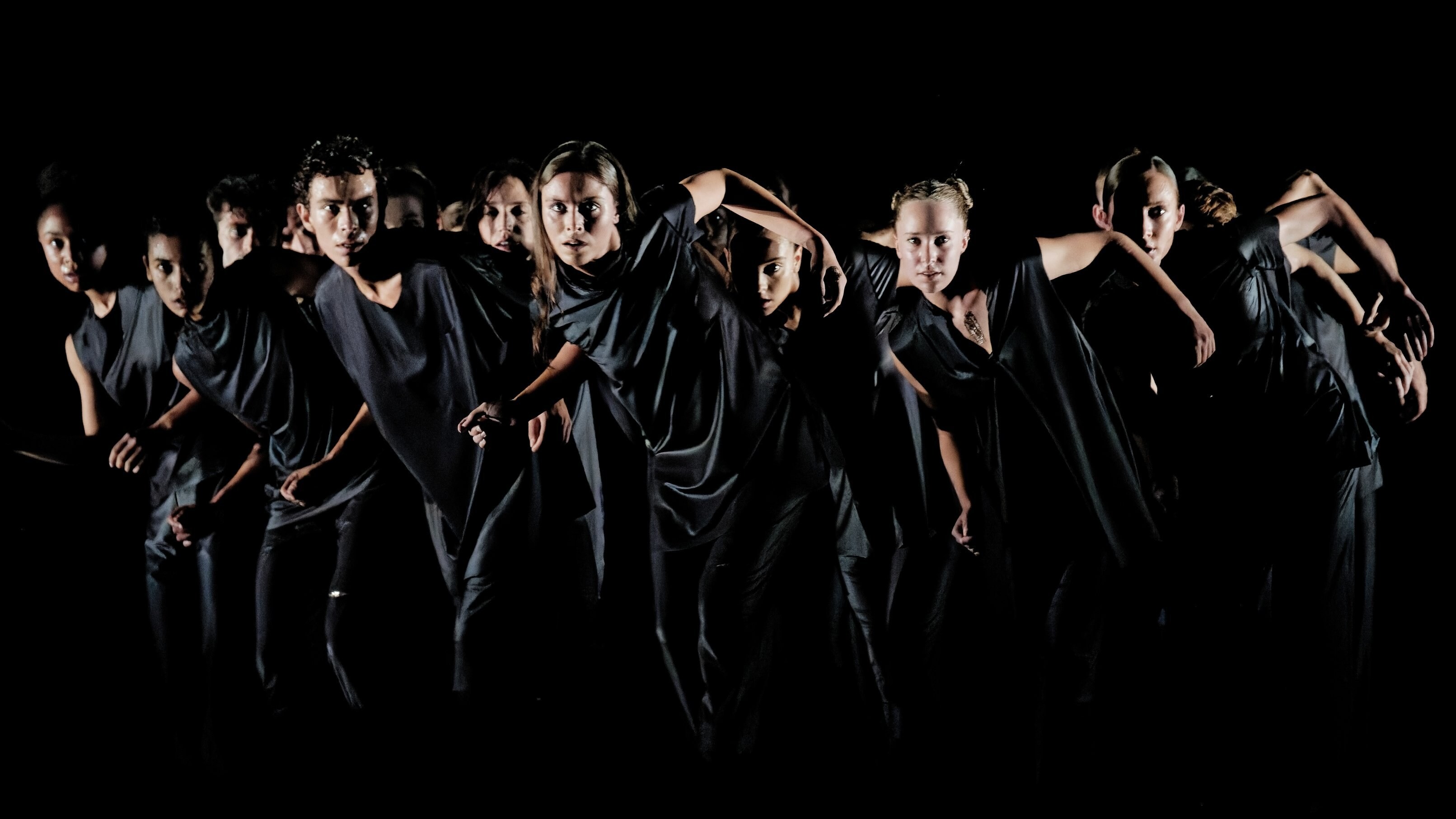 dancers in black moving as a group 