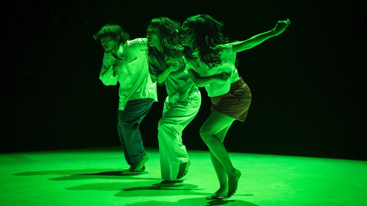 Three dancers under green stage light