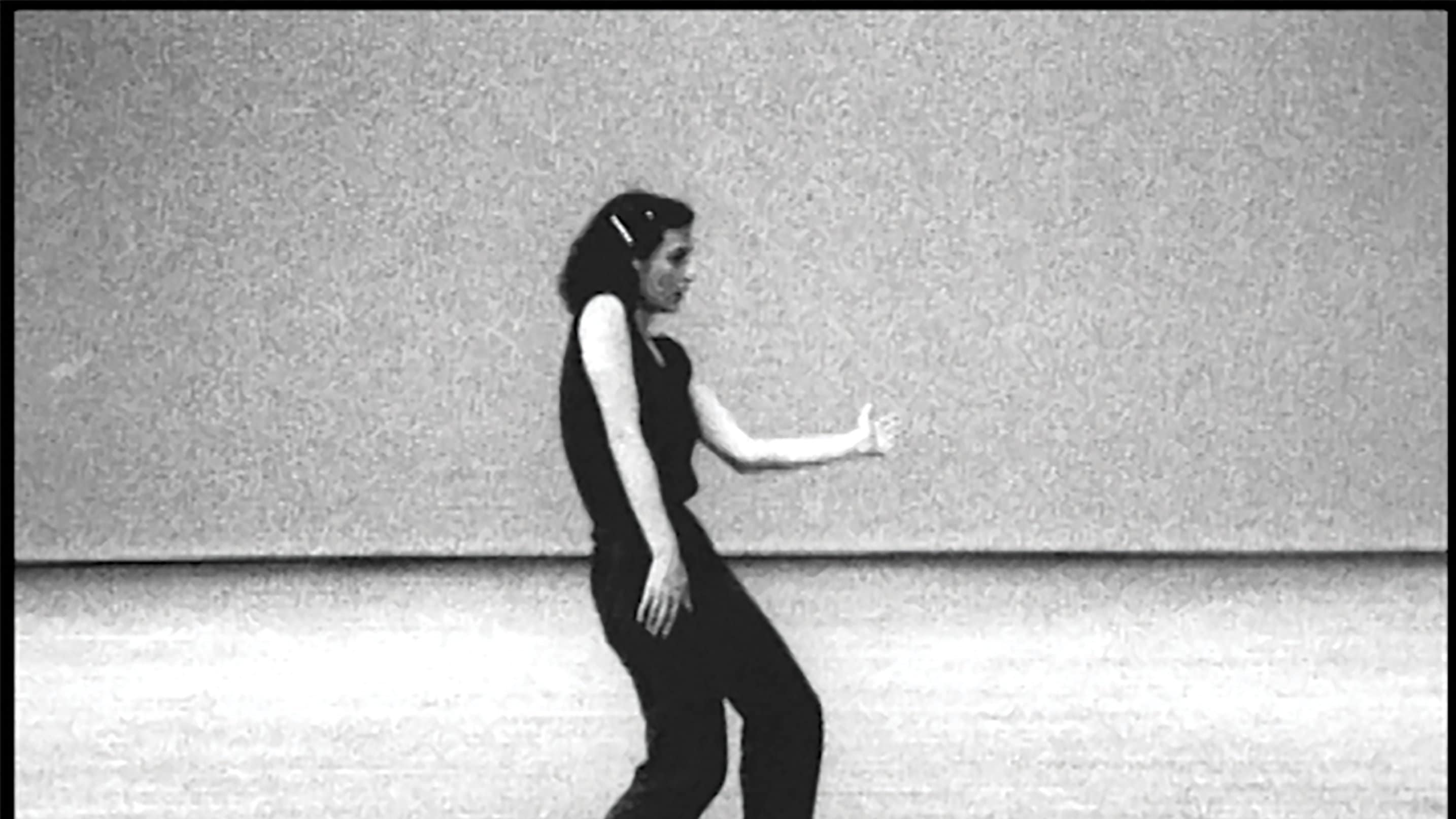 black and white picture of a dancer in black performing on an empty stage