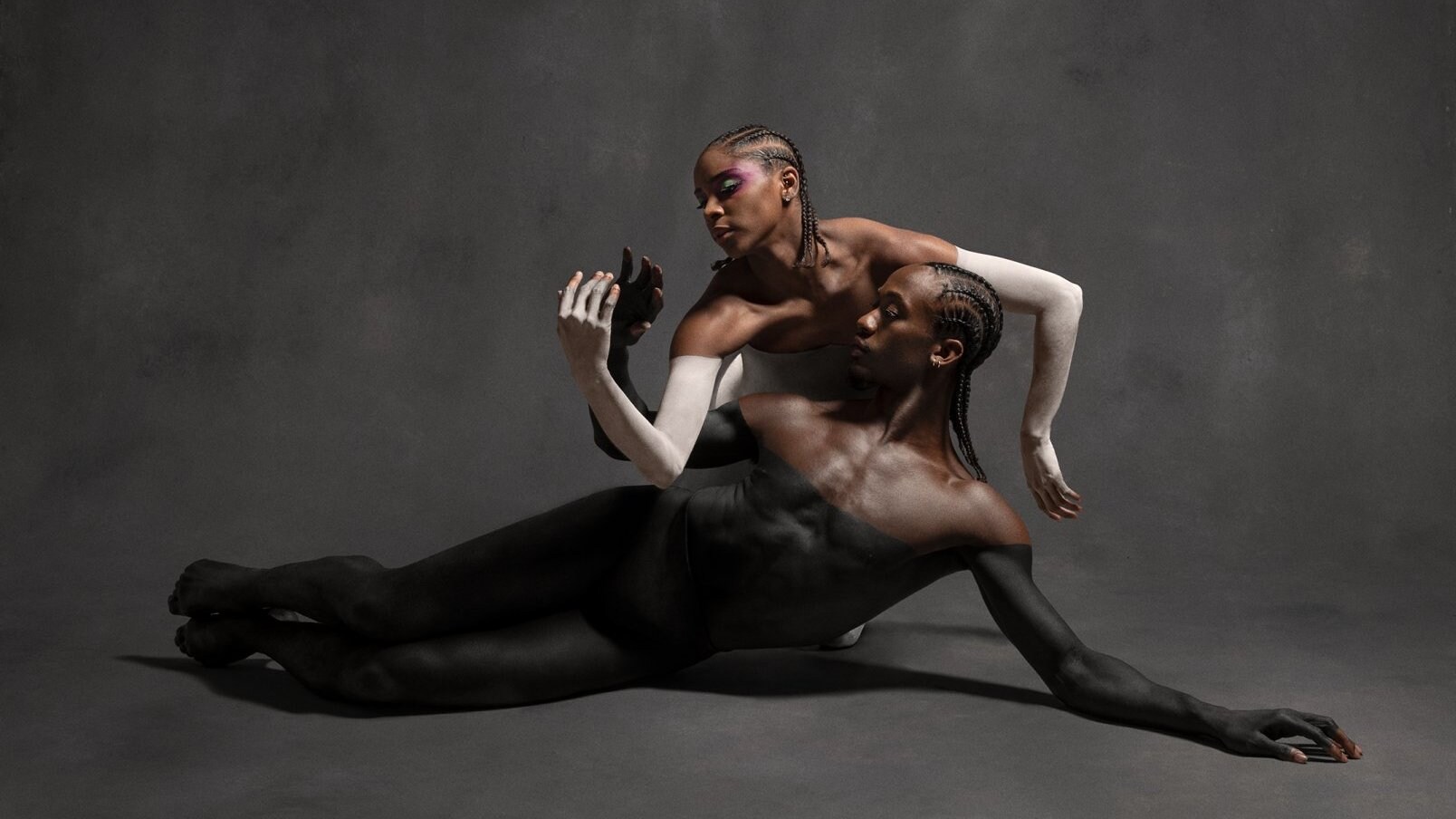 Two dancers with black and white body paint in a pose.