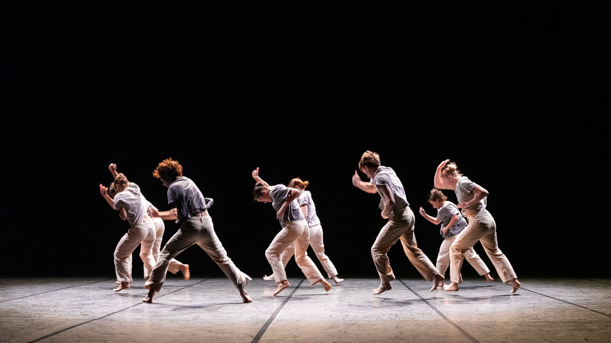 dancers running, wearing white, black scenography
