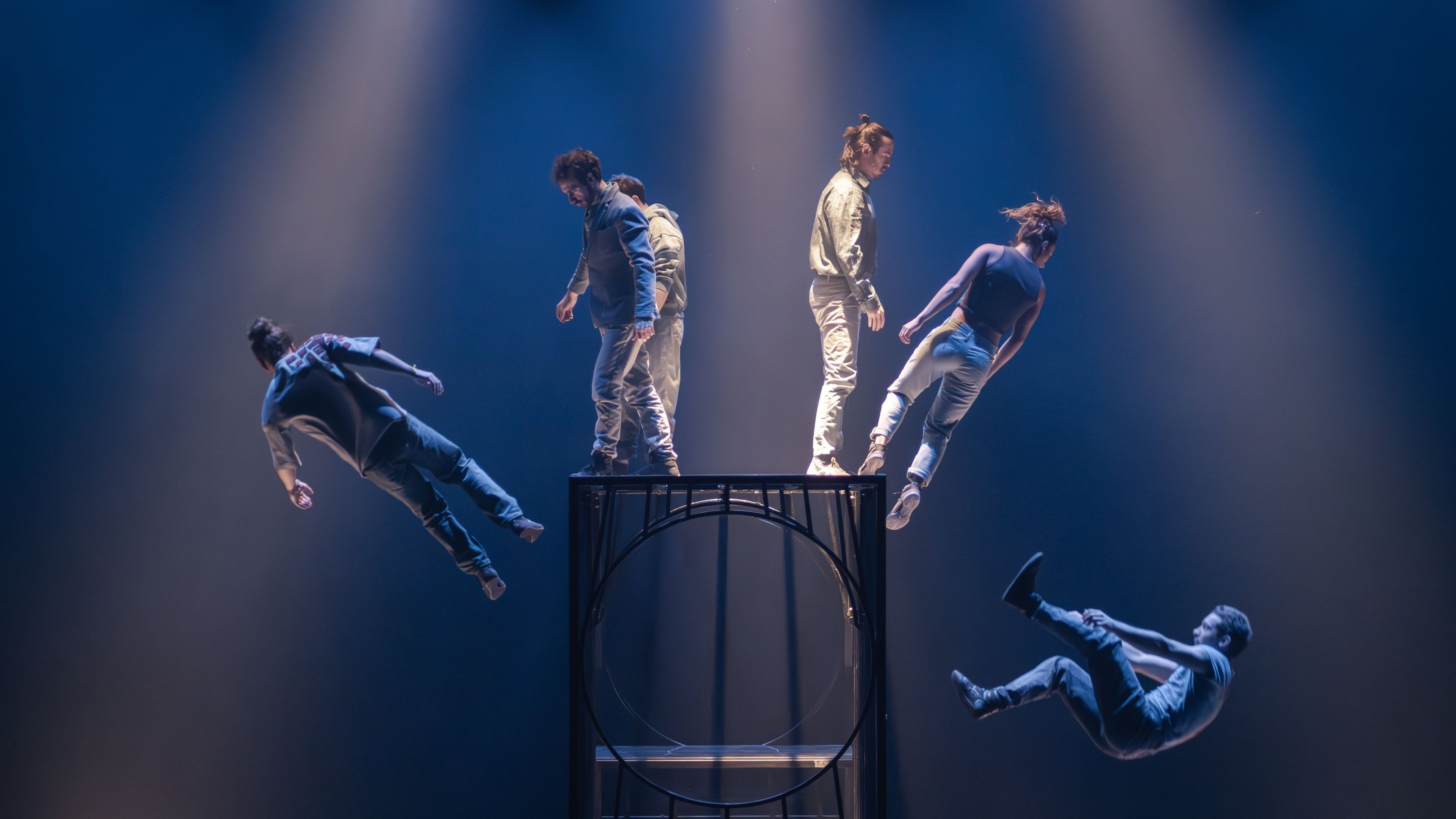 Dancers levitating around a metal cage on stage