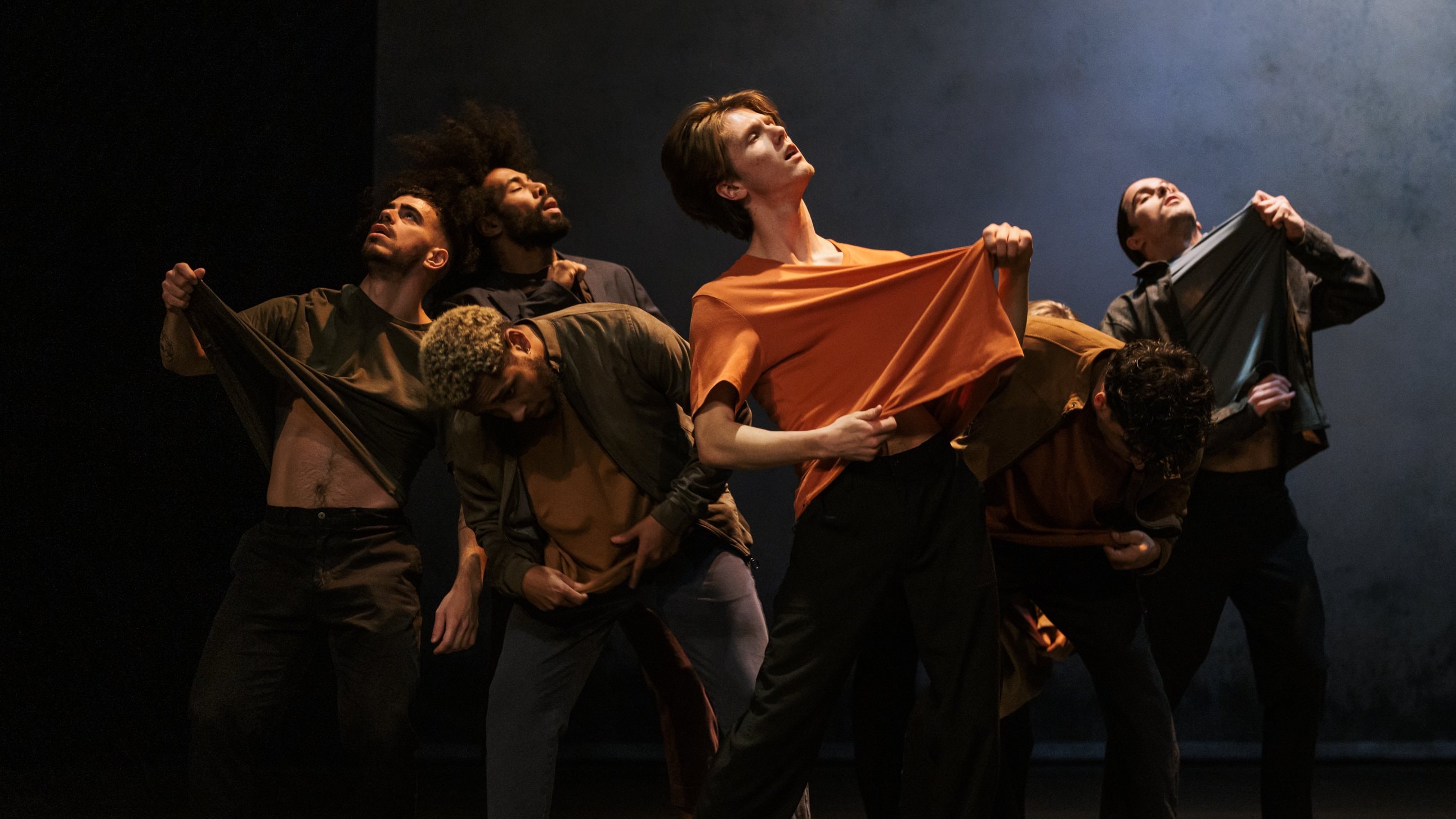 Group of six dancers in a circle lifting their t-shirts